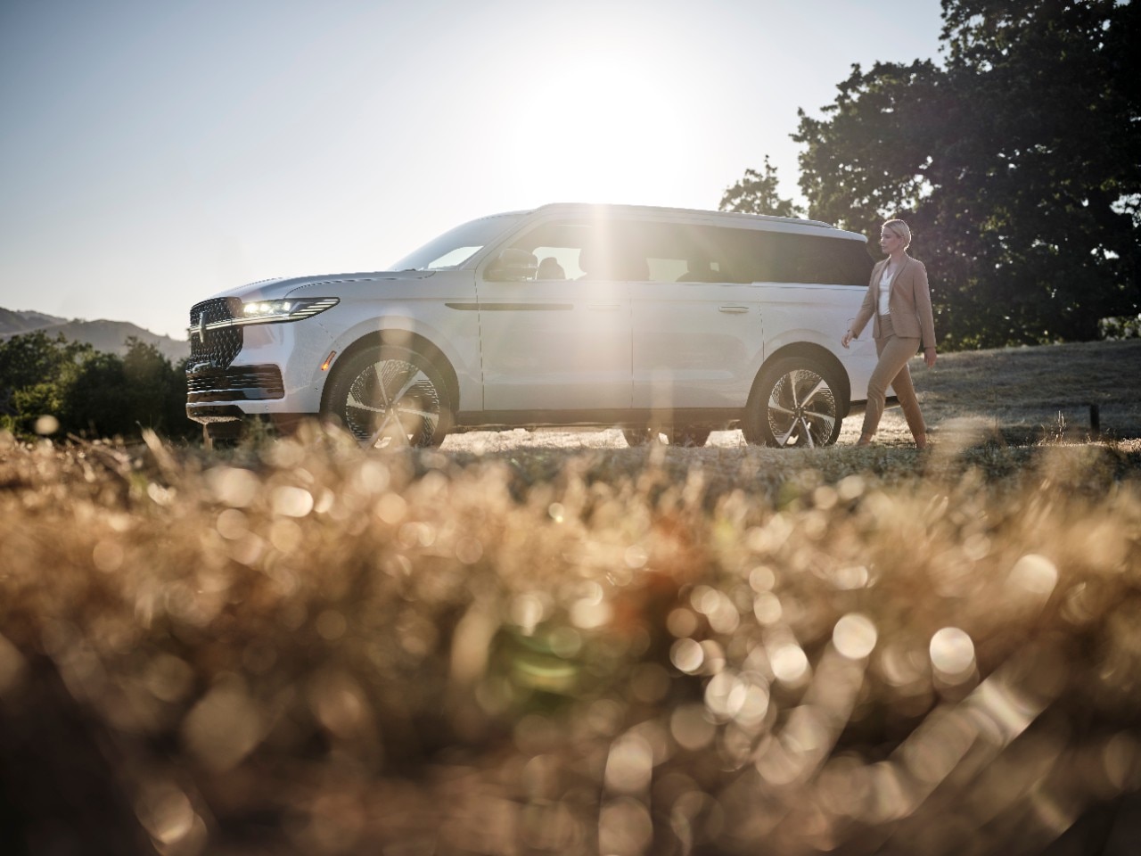 The Lincoln Navigator in white shot from the ground with the sun shining from behind the vehicle